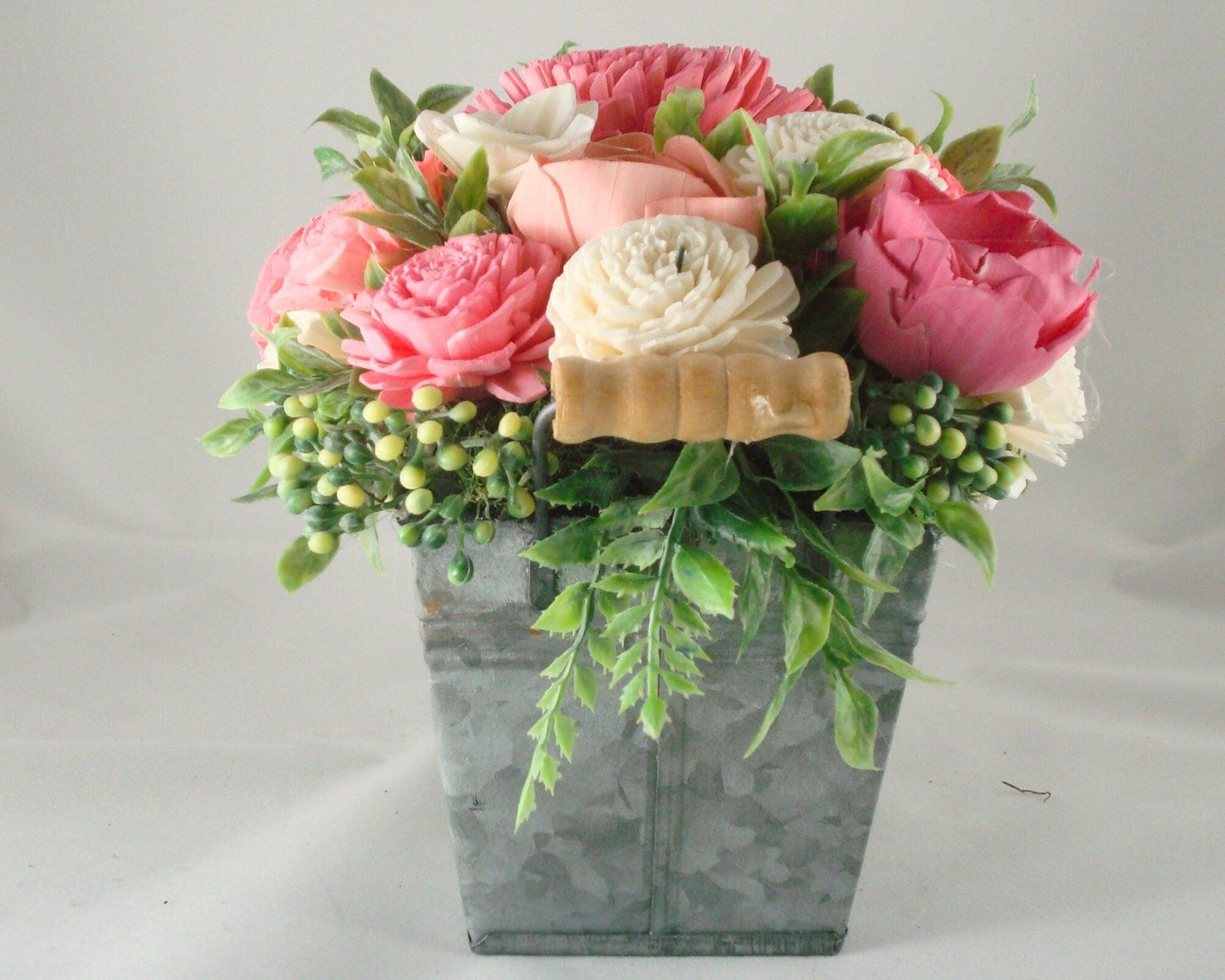 Centerpiece with hand dyed Sola flowers. Beautiful shades of pink and green wooden florals and succulents in a galvanized container