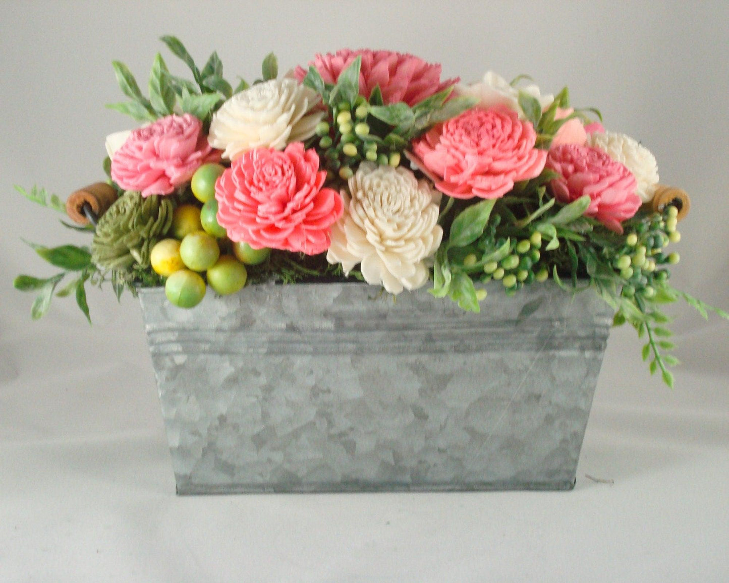 Centerpiece with hand dyed Sola flowers. Beautiful shades of pink and green wooden florals and succulents in a galvanized container