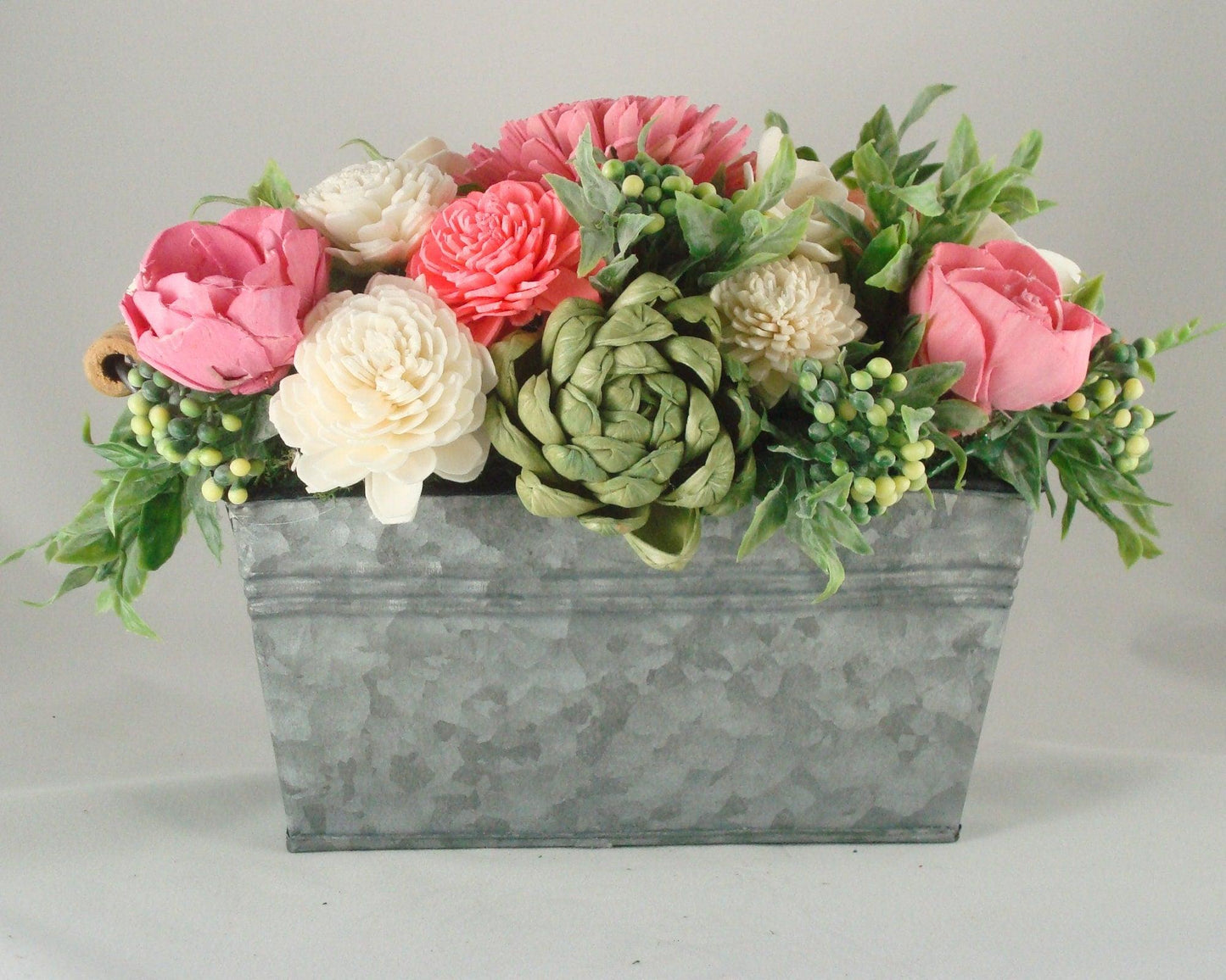 Centerpiece with hand dyed Sola flowers. Beautiful shades of pink and green wooden florals and succulents in a galvanized container