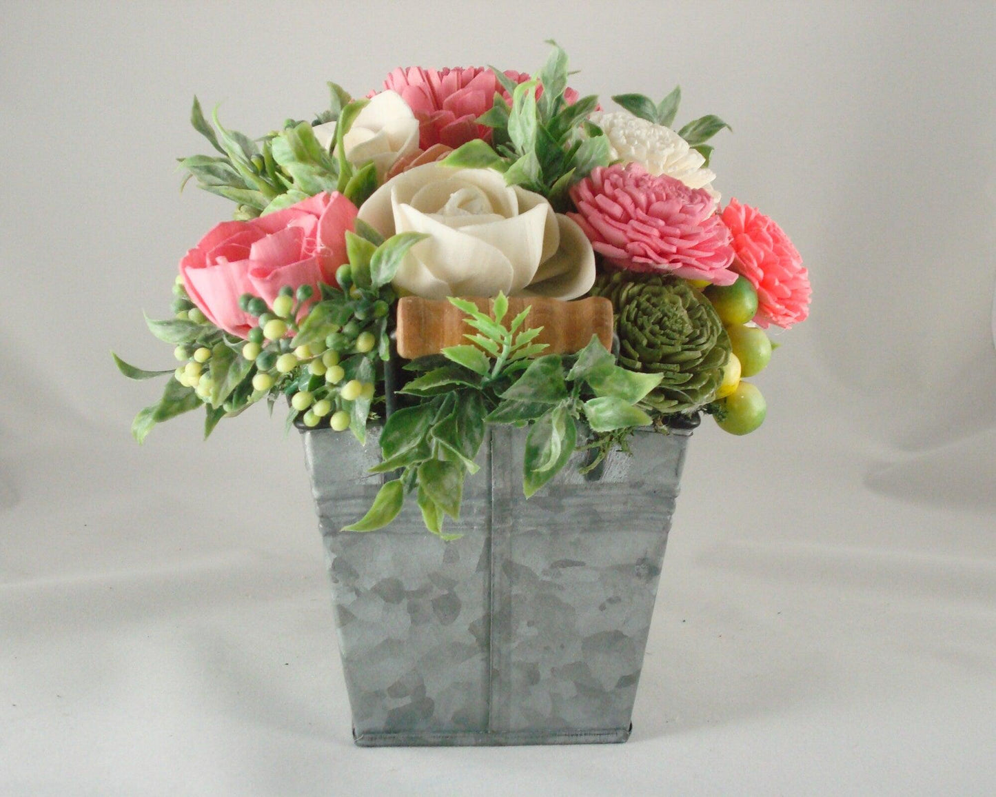 Centerpiece with hand dyed Sola flowers. Beautiful shades of pink and green wooden florals and succulents in a galvanized container